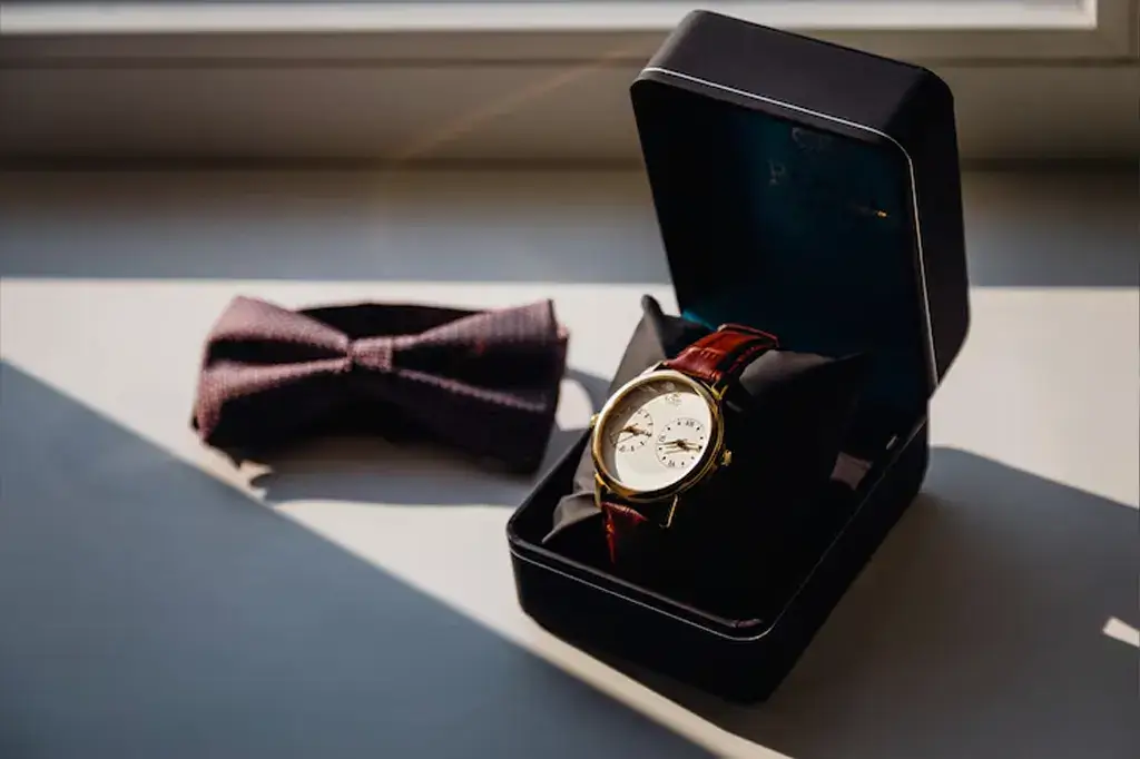 Relógio de pulso masculino e feminino com pulseira de couro e acabamento metálico, personalizado com o logotipo corporativo gravado no mostrador, apresentado dentro de um estojo de luxo.